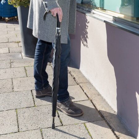 Sicherheitsschirm Gummikappe Herren - ein Herr mit Schirm als Gehstock mit Kappe zum Schutz der Metallspitze