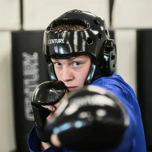 Century Kopfschutz Schüler Sparring schwarz – Junge mit Helm und Boxhandschuhe Angriff