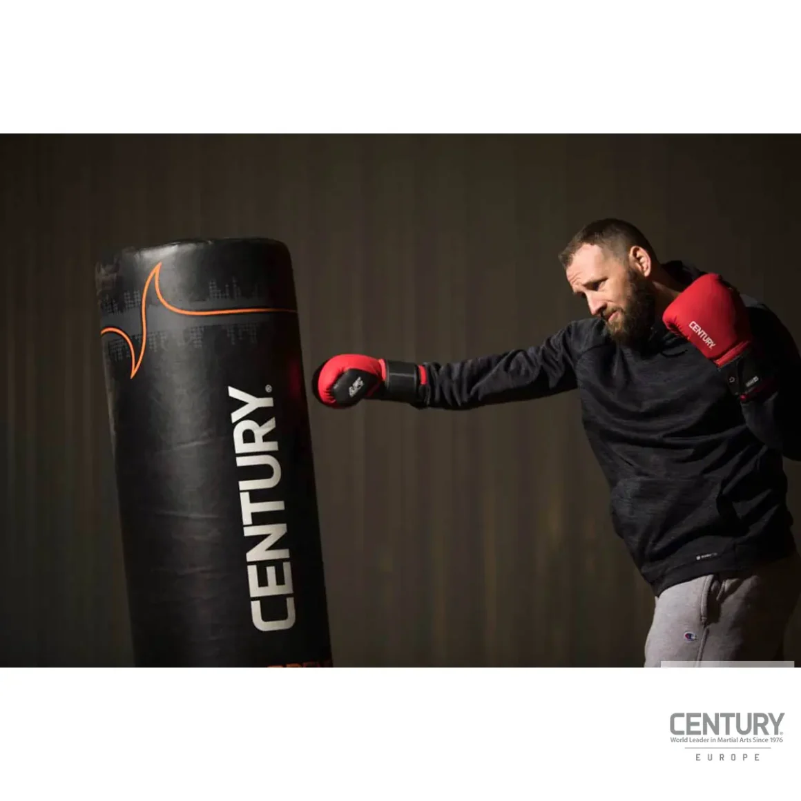 Century Brave Boxhandschuhe rot-schwarz - Kampfsportler boxt auf Sandsack