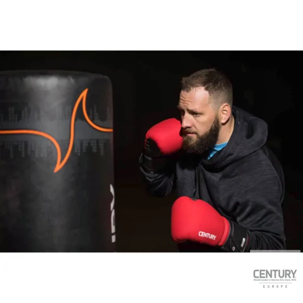 Century Brave Boxhandschuhe rot-schwarz - Kampfsportler schlägt auf Boxsack