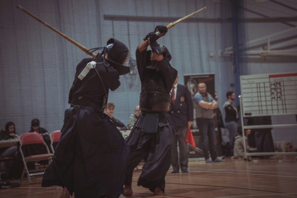 Kendo Shinai Kampftraining in einer Sporthalle - 2 Kendoka Kämpfer erheben ihre Shinais