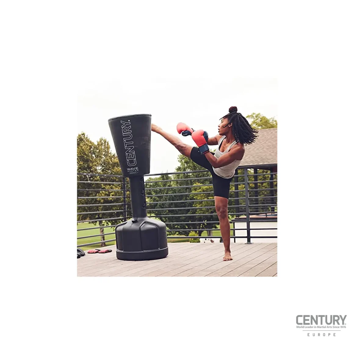 Century Uppercut Wavemaster Standboxsack mit Nummerierung schwarz-weiß - Kampfsportlerin kickt mit dem rechten Fuß am oberen Teil auf den Boxsack