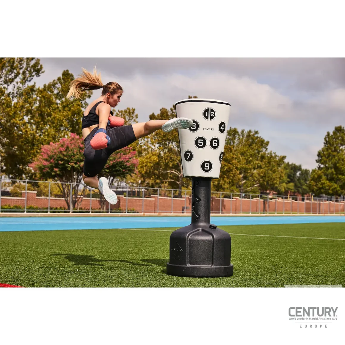 Century Uppercut Wavemaster Standboxsack mit Nummerierung schwarz-weiß - Kampfsportlerin führt Sprungkick auf Boxsack aus