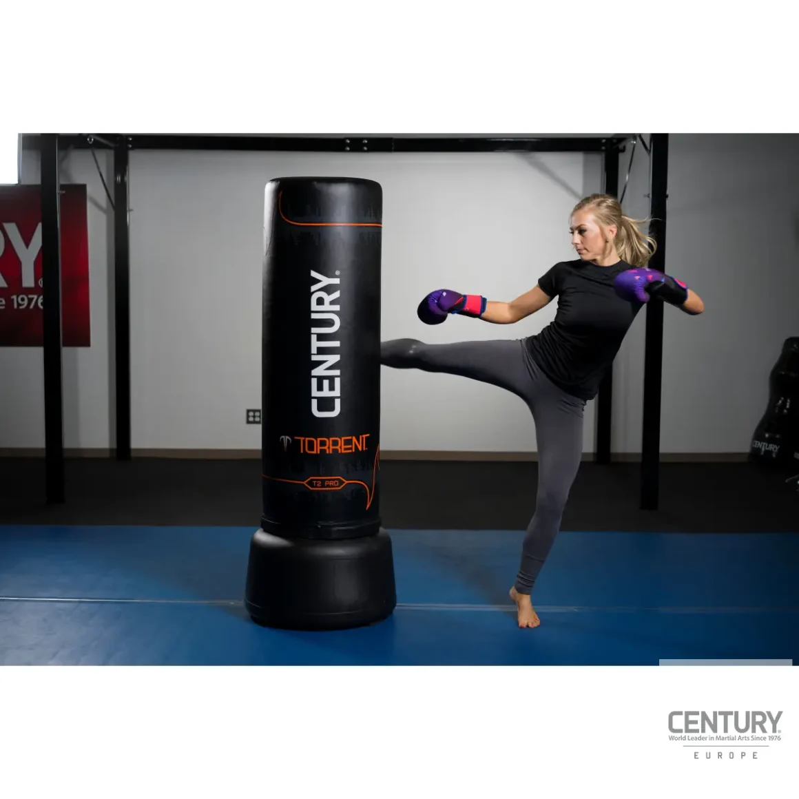 Century Torrent T2 Pro Standboxsack schwarz - Sportlerin kickt mit dem rechten Fuß an die mittlere Hälfte des Boxsacks