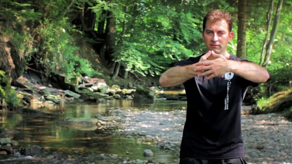 Zhong Xin Dao Die Kampfkunst der Achtsamkeit - ein Mann in Trainingskleidung steht draußen in der Natur an einem Bach und übt