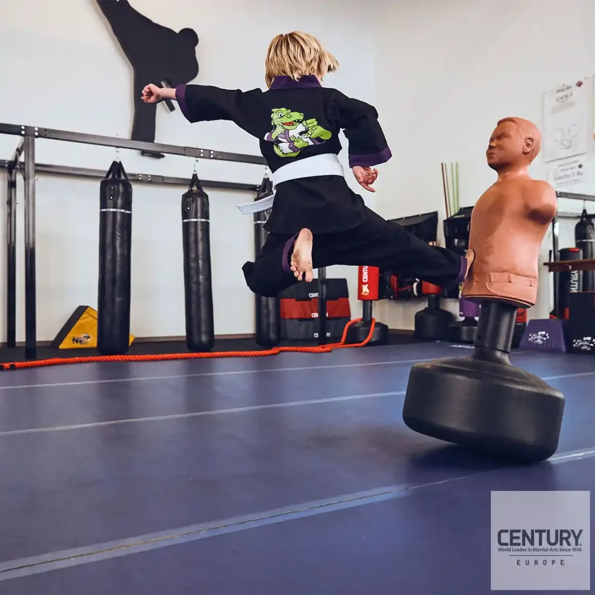 Century Lil Dragon Uniform schwarz - junger kampfsportler führt Sprungkick auf CENTURY Bobby Bully Kinder Boxdummy aus.