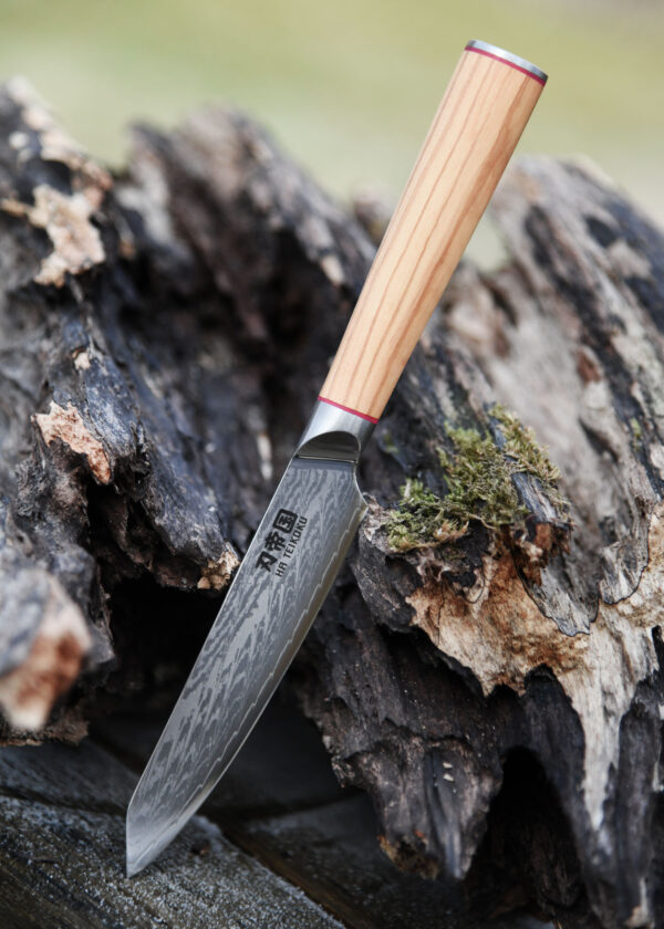 Battle Merchant Allzweckmesser Damaststahl Olivenholz Griff - Messer lehnt an ein altes grause Holzstück auf einem Holztisch
