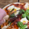 Battle Merchant Pizzaschneider Pizzaroller Templer Schwert Edelstahl, Eschenholz, Messing, Emaille - in einer Hand, die gerade die Pizza Mozarella schneidet, Nahaufnahme von oben