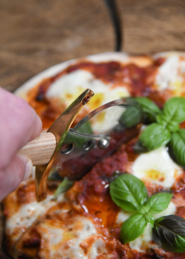 Battle Merchant Pizzaschneider Pizzaroller Templer Schwert Edelstahl, Eschenholz, Messing, Emaille - in einer Hand, die gerade die Pizza Mozarella schneidet, Nahaufnahme von oben