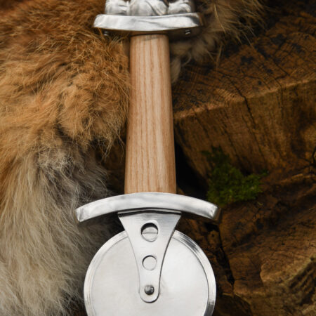 Battle Merchant Pizzaschneider Pizzaroller Wikinger Schwert Edelstahl, Eschenholz, Stahl - liegt auf Holzscheite und braun-weißem Tierfell