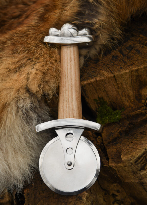 Battle Merchant Pizzaschneider Pizzaroller Wikinger Schwert Edelstahl, Eschenholz, Stahl - liegt auf Holzscheite und braun-weißem Tierfell