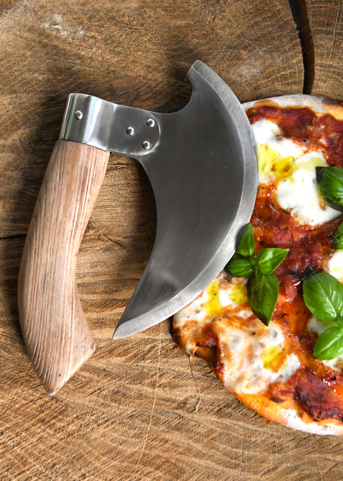 Battle Merchant Pizzaschneider Wiegemesser Wikinger Bartaxt für Pizza und Kräuter Edelstahl, Eschenholz - liegt auf einer Holzscheibe zum Teil auf einer Pizza
