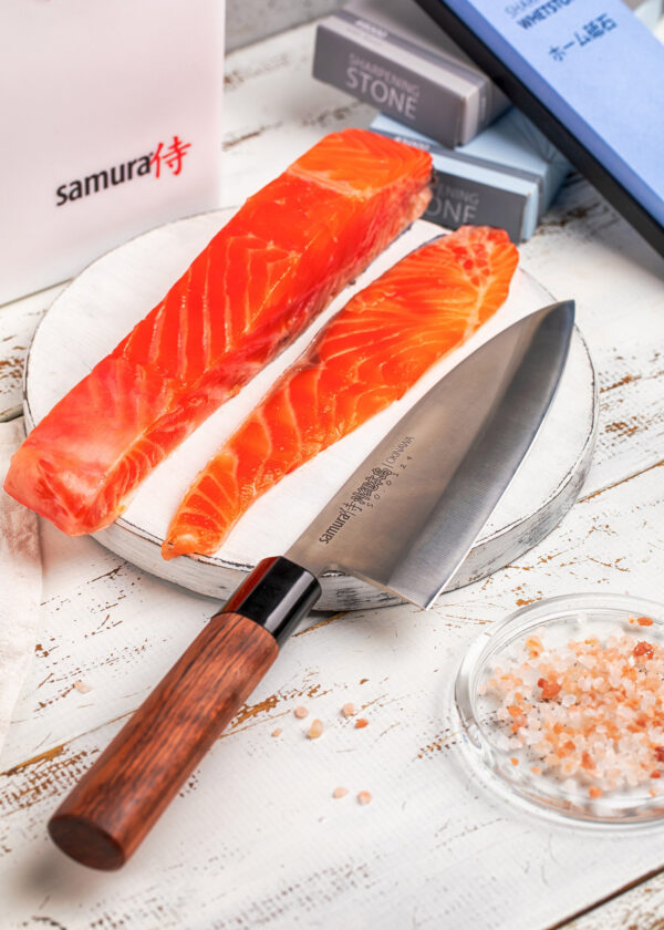 Samura Okinawa Deba Küchenmesser 170 mm braun schwarzer Griff - Messer liegt auf einem Teller mit Lachs und daneben Himalayasalz
