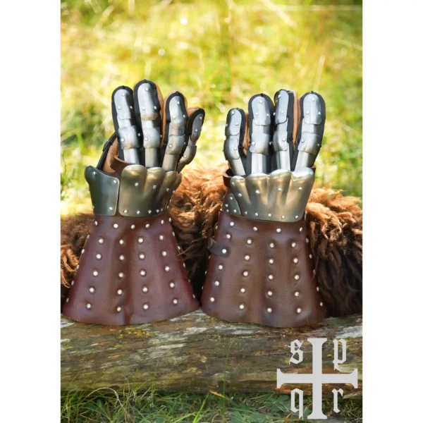 Battle Merchant mittelalterliche Panzerhandschuhe Visby 14. Jh. braun - Beide Handschuhe stehend auf dem Gehölz an Fell gelehnt, Wiese im Hintergrund
